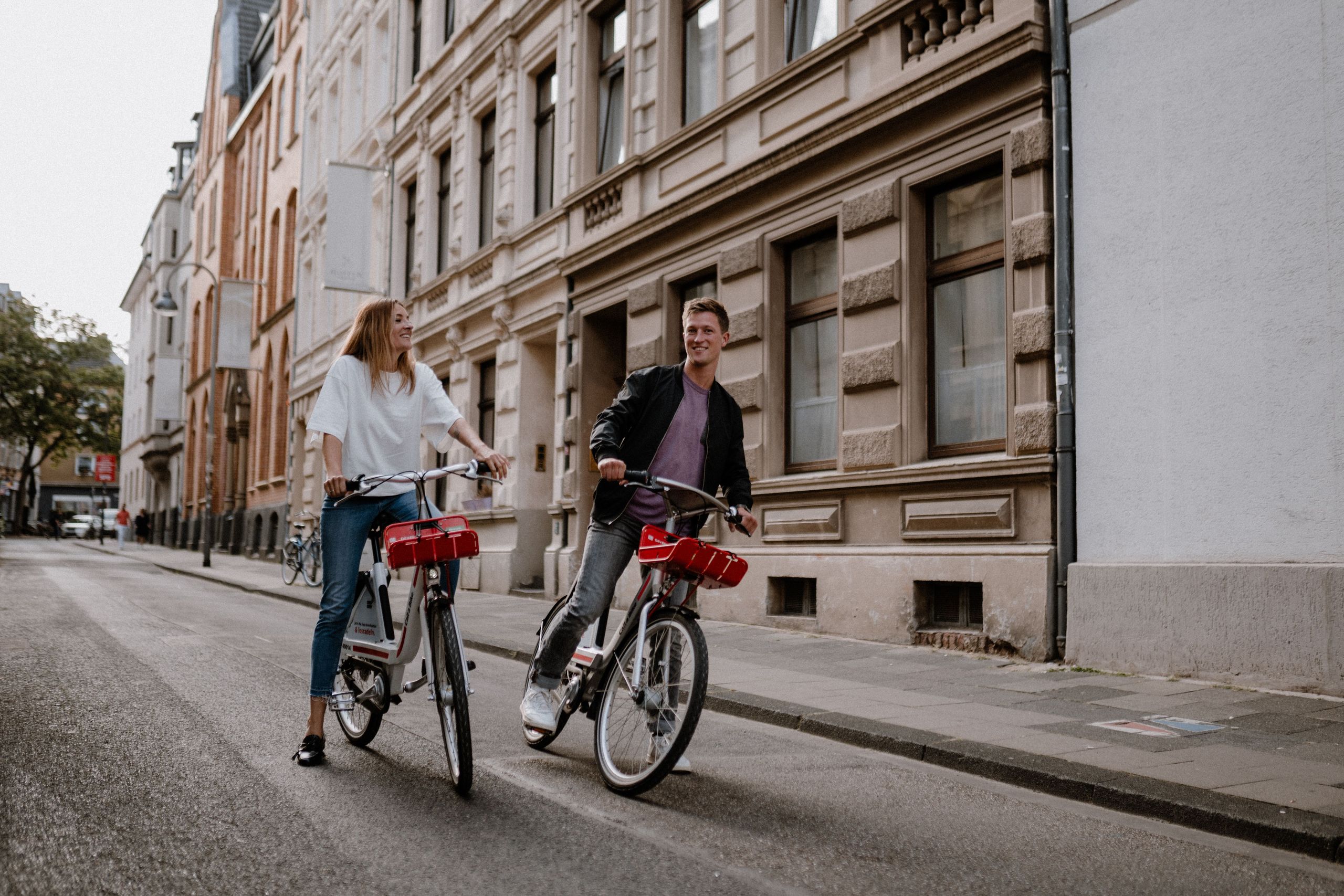 Woman and man ride their Call a Bike bicycles through the city center